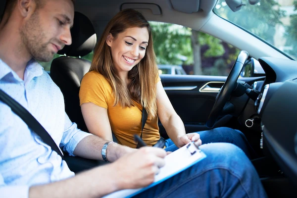 Formateur auto-école échangeant avec une élève en voiture